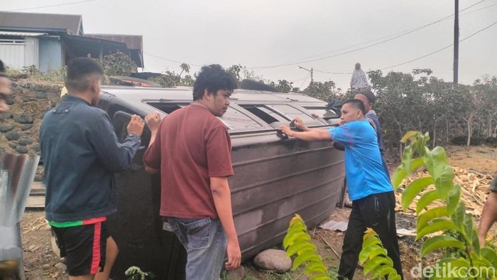 Warga saat mengevakuasi minibus terguling gegara sopir diduga mabuk.