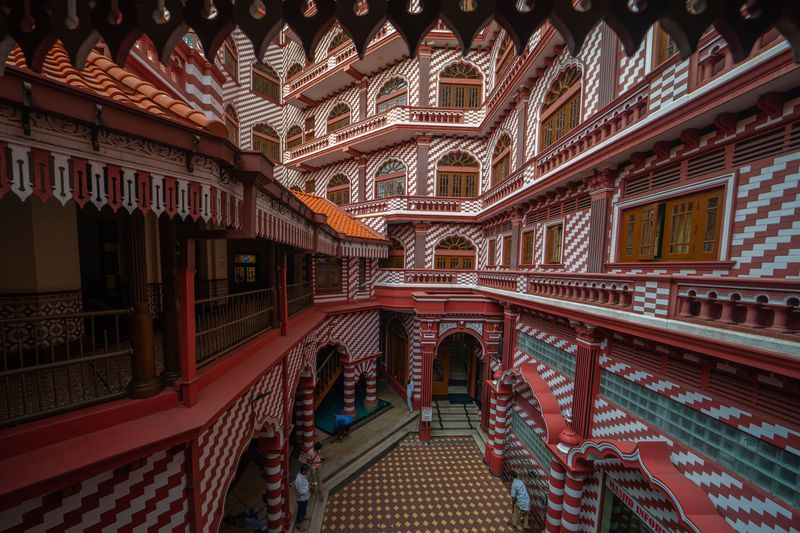 1250863895 An inside view of the red mosque in Colombo, Sri Lanka, on April 7, 2023. The Colombo Red Mosque, also known as Jami Ul-Alfar Masjid, is literally an architectural wonder for the world that would stun you with its unusual color patterns and unconventional yet amazing design. Located in Colombo district, this oldest mosque towers over the buildings and streets in the neighborhood with its tall minarets and was once a reliable landmark for the sailors coming towards Colombo port. Colombo had always been a welcoming hub for international trade, where Arabs frequently visited and populated enormously. They had to perform their five mandatory daily rituals. For that reason, the Indian Muslim Community was commissioned to put up a mosque in Pettah. Work commenced in 1908, and the construction of the Colombo Red Mosque (Jami-Ul-Alfar Mosque) was finished in just one year. Habibu Labbe Saibu Labbe was the chief designer of the building, and he relied on Indo-Saracenic and Neo-classical architectural styles. In 1975, the mosque's capacity was extended to as much as 10,000. The oldest mosque in Colombo is literally an interesting tourist destination. (Photo by Thilina Kaluthotage/NurPhoto via Getty Images)