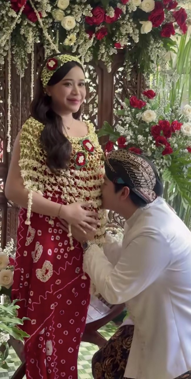 Ikuti tradisi adat Jawa, di prosesi siraman Jodie tampil kenakan kain jumputan berwarna merah, lengkap dengan cape dan bandana ronce melati. Sementara suaminya tampil dengan beskap putih dipadukan dengan kain lilit batik coklat dan blangkon untuk menutup kepalanya.&nbsp;Foto: Instagram/@brisiajodie96