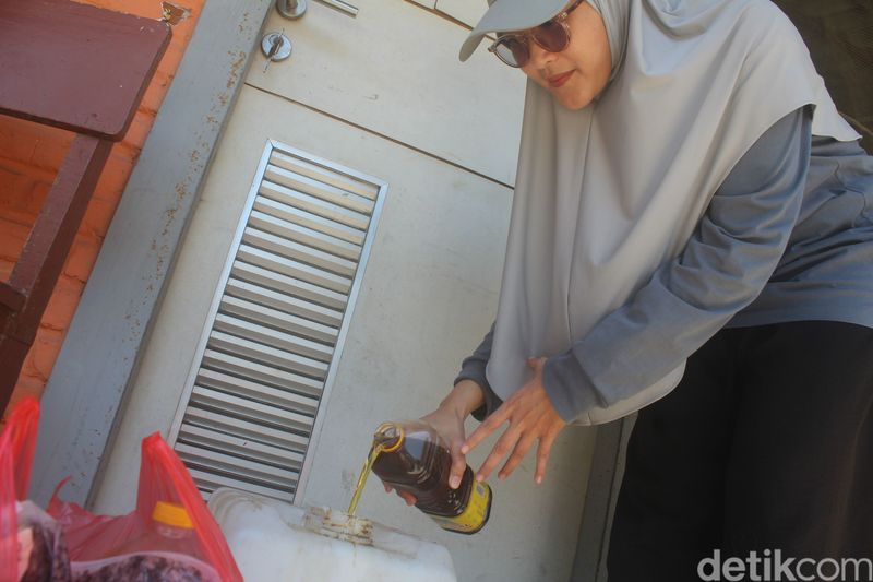 Hamidah saat menuangkan minyak jelantah ke jeriken di Balai RT
