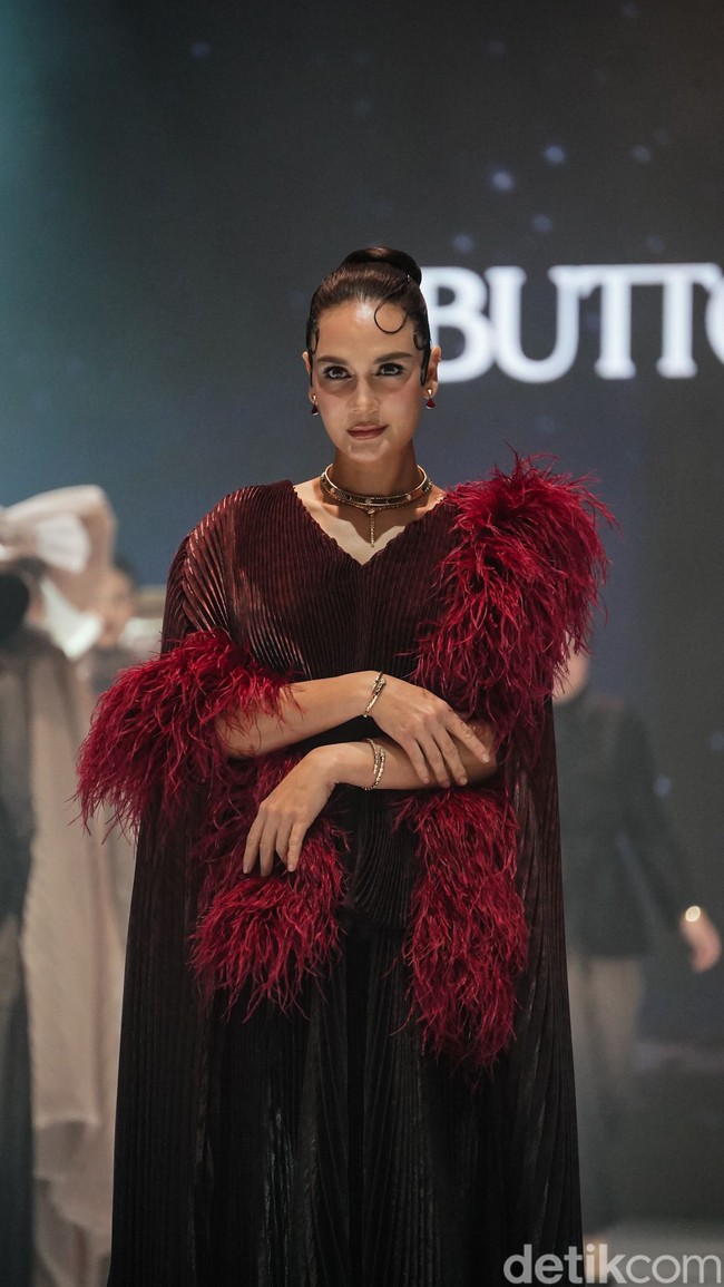 Luna Maya mengenakan gaun pleats bernuansa merah marun gelap dan aksesori syal berhias bulu-bulu. Penampilannya disempurnakan dengan kalung choker emas. Foto: Tsaltsabillah Khairunissa/Wolipop