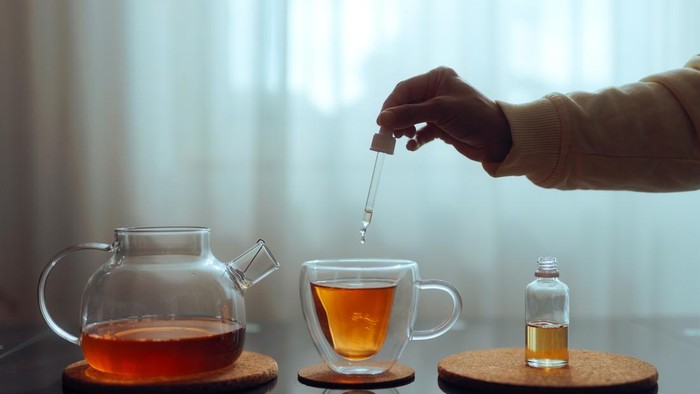 Person using sugar alternatives for sweetening herbal drinks