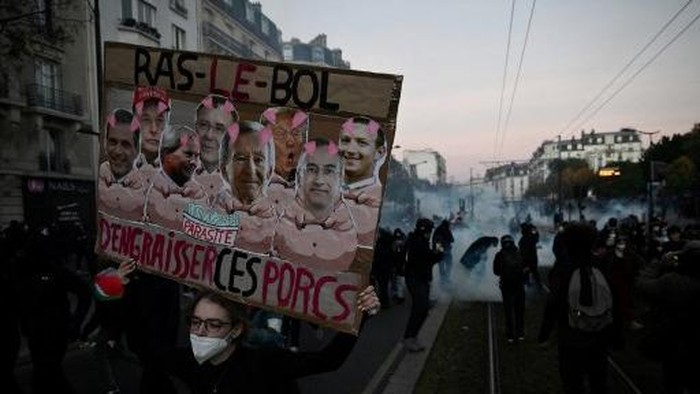 A person wearing a Star Wars Jedi costume and holding a French national flag walks away from tear gas during clashes between protesters and law enforcement at the end of a demonstration part of a nationwide day of protests over the rising cost of liv