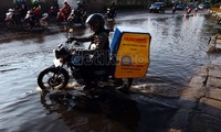 Seorang pengguna sepeda motor sedang melintasi genangan air yang tingginya sekitar 15 cm.