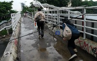 Seorang pejalan kaki harus melalui kabel listrik yang melilit JPO. Rengga Sancaya/detikcom.