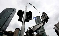 Pekerja mengganti lampu pengatur lalu-lintas yang telah rusak. Kerusakan lampu pengatur lalu-lintas mendorong pengendara terjebak saling serobot.
