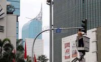 Seorang pekerja sedang memperbaiki lampu lalu lintas di kawasan Bunderan HI, Jakarta.