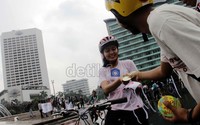 Pengendara sepeda menerima masker dan pin yang dibagikan. Hasan Alhabshy/detikcom.