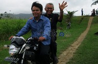 Menteri Pekerjaan Umum Djoko Kirmanto melambaikan tangan saat dibonceng sepeda motor menuju Camar Bulan.