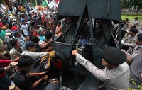Polisi berusaha menjaga kawat berduri agar tidak dijebol pendemo.