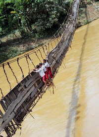Tiga murid SD Negeri 02 Sangiangtanjung meniti jembatan miring saat menyebrangi Sungai Ciberang menuju rumah mereka, Selasa (17/1). Kurangnya perhatian Pemda terhadap insfrastruktur di desa ini membuat anak-anak ini bak menantang maut ketika pergi dan pulang sekolah. ANTARA/Asep Fathulrahman.