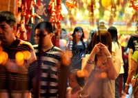 Seorang gadis warga Tionghoa sedang berdoa di depan pintu keluar klenteng Xian Ma.