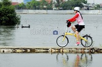Seorang penggemar sepeda melintasi tambak warga. Trend bersepeda cenderung naik karena kebutuhan olahraga dan kesenangan tersendiri.