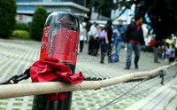Sebuah pita merah diikat dipagar trotoar yang rusak.
