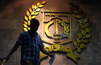 Seorang pegawai DPRD DKI Jakarta, melewati lambang dari DPRD DKI Jakarta yang berada di ruang Rapat Paripurna, Jumat (27/01).