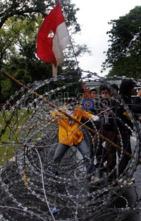 Mahasiswa berusaha menembus kawat berduri.