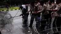 Polisi berupaya mengembalikan kawat berduri seperi posisi sebelumnya.