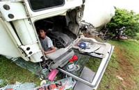 Seorang kenek duduk di dalam truk semen yang terguling di pinggir jalan tol JORR Cikunir.