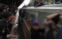 Para penumpang tetap nekat menaiki atap kereta meskipun atap kereta licin setelah diguyur hujan tadi sore (10/02)