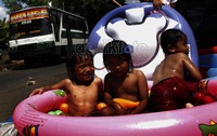 Anak-anak mandi bola di pinggir jalan raya.