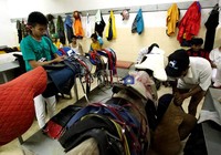 Dua joki tengah mengecek peralatan pelana kuda, sebelum dimulainya perlombaan.