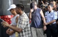 Petugas mengawal dua narapidana (napi) asing saat dilakukannya evakuasi pasca kerusuhan di LP Kerobokan. Dari 32 napi, 13 di antaranya adalah napi asing. ANTARA/Nyoman Budhiana.