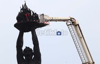 Selain membersihkan petugas juga mengganti lampu yang berada di bagian obor patung