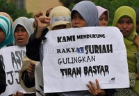 Massa Akhwat HTI Sulsel membawa poster dukungan atas rakyat Suriah untuk menggulingkan Presiden Assad.