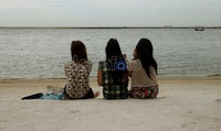 Tiga wanita ini sedang menikmati sejuknya udara pantai dan pasir putih di kawasan pantai timur Ancol.