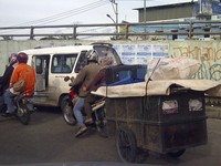 Pengendara Honda Supra X menarik gerobak yang diikat ke saddle bagian belakang motor. Awas hati-hati nyenggol yang lain.