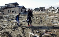 Seorang warga bersama dua anaknya mengunjungi tempat di mana rumah mereka tersapu oleh tsunami setahun yang lalu.Reuters / Toru Hanai