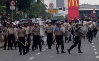 Berbekal tameng dan kayu, polisi berusaha membubarkan demonstran.
