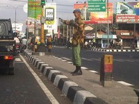 Dengan mengenakan seragam hansip gayanya menirukan polisi lalu lintas.