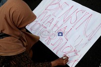Seorang demonstran menuliskan poster Bensin mahal motor mogok dalam aksi di kantor Kementrian Energi dan Sumber Daya Mineral (ESDM).