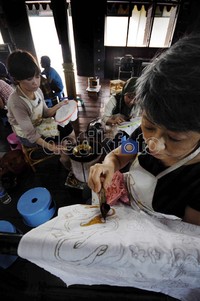 Dua orang warga Jepang bersama beberapa perajin mengerubungi kompor dengan wajan kecil yang berisi malam.