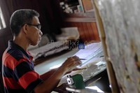 Seorang perajin batik sedang membuat pola atau motif.