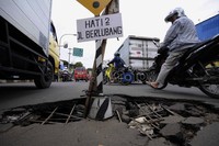 Kendaraan melintasi lubang menganga di Jalan Teluk Gong Raya, Jakarta Utara, Selasa (20/3).