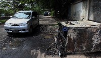 Sebuah kendaraan mobil melintasi lokasi pembakaran pasca keributan antara warga asal Ambon dan warga setempat di Perumahan Titian Indah, Kalibaru, Bekasi.