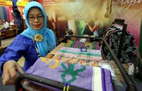 Salah satu pengunjung pameran Kerajinan Nasional Indonesia 2012, tengah melihat kain tenun yang terbuat dari serat daun doyo, yang merupakan hasil kerajinan daerah Kalimantan Timur.