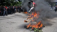 Seorang mahasiswa UIT melompati api dalam aksi unjuk rasa di depan SPBU Pettarani-Rappocini.