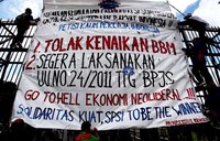 Para buruh memasang spanduk berisi penolakan kenaikan harga BBM di pagar gedung DPR, Jakarta.