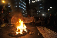 Sejumlah aktivis mahasiswa membentang spanduk di belakang ban yang dibakar untuk memblokade jalan di depan Kampus YAI, Salemba, Jakarta, Kamis (29/3) malam. ANTARA/Ismar Patrizki.