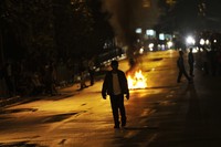 Seorang pejalan kaki berjalan di depan benda yang dibakar aktivis mahasiswa untuk memblokade jalan di depan Kampus UKI, Salemba, Jakarta, Kamis (29/3) malam. ANTARA/Ismar Patrizki.