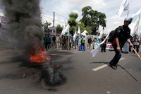 Para mahasiswa membakar ban di tengah jalan.