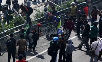 Para buruh menjebol pagar pembatas tol di depan gedung DPR, Jakarta.