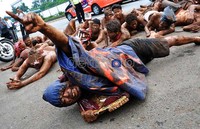 Seorang pendemo yang telah melumuri tubuhnya dengan tanah merangkak menuju gerbang gedung DPR sambil memeluk lambang negara, Garuda.