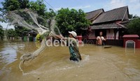 Di tengah banjir, seorang warga mencari ikan.