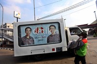 Mobil boks berwarna putih itu, berisi running poster di setiap sisinya.