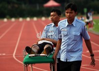 Seorang atlet junior putra, tengah ditandu oleh petugas panitia, saat pingsan usai melewati garis finis.