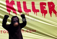 Salah satu pendemo yang memakai kostum orangutan melakukan aksi dengan latar belakang spanduk yang bertuliskan Killer, di depan Kantor Jaksa Agung, Jakarta.